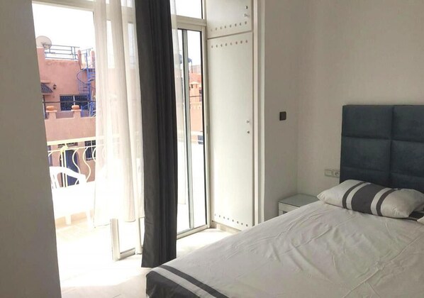 A bedroom with a bed, a wardrobe, and a view of the outside balcony.