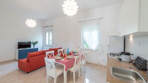 Un espacio habitable compacto con comedor, kitchenette y televisor en la sala.