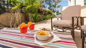 Una mesa con dos vasos de bebida roja, un bol de patatas fritas y un bol de frutos secos.