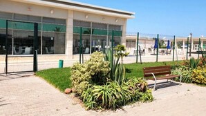 A building with large windows, a paved walkway, and a bench. - Beautiful pool view apartment in Ola Blanca 4533 (Sidi Rahal)
