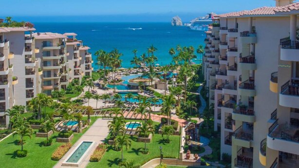 Un resort con varias piscinas, palmeras y vistas al océano.