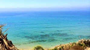Uitzicht op de kust met helderblauw water en een zandstrand.