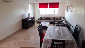 Un salon avec un canapé, une table à manger et des chaises, ainsi qu’un téléviseur.