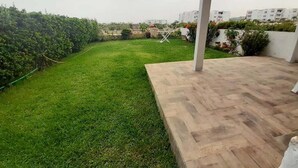 Un jardin sur le toit, avec une terrasse en bois, une zone herbeuse et une clôture blanche.
