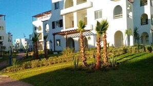 A modern hotel with multiple white buildings, palm trees, and a well-maintained garden. - Beautiful Cabo pearl apartment 4442 (Cabo Negro)