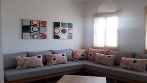 A modern living room with a grey sectional sofa, decorative pillows, abstract wall art, and a wooden coffee table. - Beautiful Cabo pearl apartment 4442 (Cabo Negro)