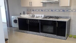 A kitchen with a gas stove, oven, and washing machine in the corner. - Beautiful Cabo pearl apartment 4442 (Cabo Negro)