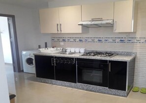 Réfrigérateur, un four, surface de cuisson, vaisselle et ustensiles