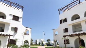 A pathway leading to a white building with arched windows and a pergola. - Beautiful Cabo pearl apartment 4442 (Cabo Negro)