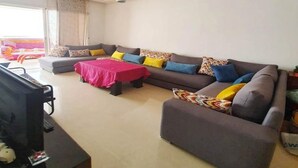 A living room with a grey sofa set, a TV, and a red table. - Wonderful apartment in Ola Blanca 4517 (Sidi Rahal)