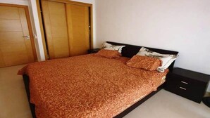 A bedroom with a bed, wooden wardrobe, and a nightstand. - Wonderful apartment in Ola Blanca 4517 (Sidi Rahal)