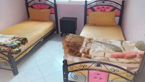 Two single beds with black frames and pink headboards, each with a yellow mattress and a brown blanket. - Apartment in Tangier City 4342 (Tanger)