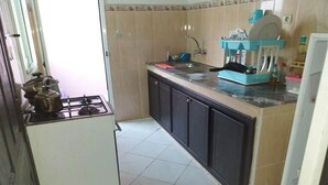 A compact kitchen with a gas stove, a sink, and a countertop with a dish rack. - Apartment in Tangier City 4342 (Tanger)