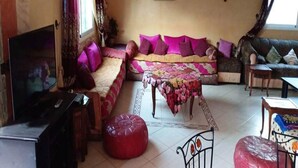 Ein Wohnzimmer mit einer Couch, einem Hocker und einem Fernseher.