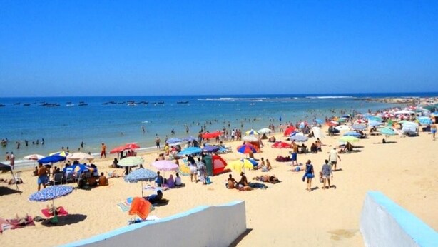 Ein überfüllter Strand mit vielen Sonnenschirmen und Menschen.
