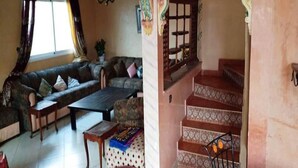 Ein Wohnzimmer mit einer Couch, einem Couchtisch und einer Treppe mit gemusterten Fliesen.