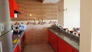 Une cuisine avec des meubles de couleur rouge, un plan de travail en granit et un dosseret carrelé.
