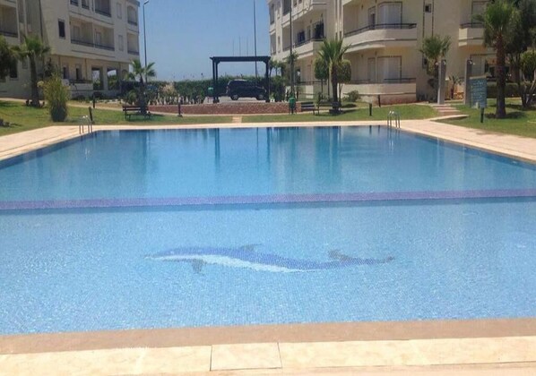 A swimming pool with a clear blue water surface, surrounded by a tiled deck.