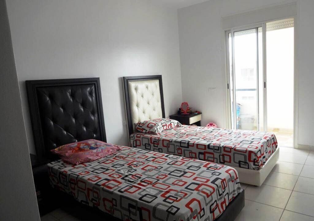 Une chambre avec deux lits, une fenêtre et une porte.