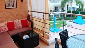 Una sala de estar con un sofá, una mesa de centro y un balcón con barandilla.