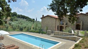 A rectangular swimming pool with a stone border, surrounded by a stone wall and a small stone building with arched windows. -  YOUR EXCLUSIVE HOLIDAY BETWEEN VINEYARDS AND CASTLES (Villa A Sesta)