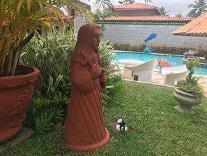 A statue of a woman in a garden with a pool and outdoor furniture. - Suites Bouganville 2 (Ipojuca)