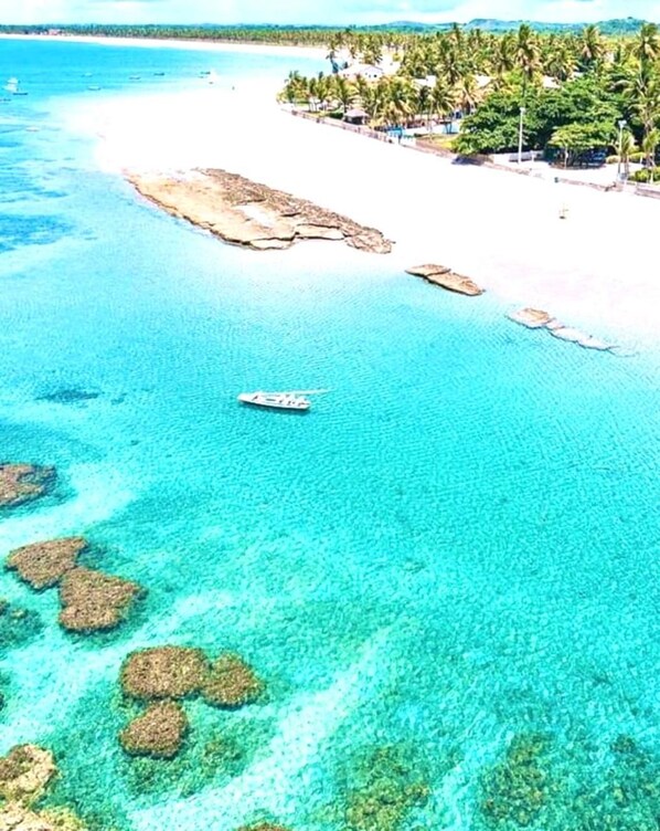 A coastal area with clear turquoise waters, a sandy beach, and a boat.