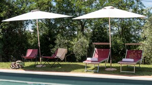 A poolside area with four lounge chairs and two umbrellas. - Villa Bellaria, in the heart of Tuscany (Lucignano)