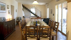 A dining area with a long wooden table set for a meal, surrounded by chairs. A staircase is visible in the background leading to another level. - Villa Bellaria, in the heart of Tuscany (Lucignano)