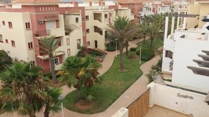 A residential complex with multiple buildings, each featuring balconies and a central courtyard with palm trees. - Apartment in Saidia 4305 (Saidia)