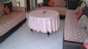 A living room with two sofas, a round coffee table, and a patterned rug. - Apartment foot in the water in Sary beach 3958 (Sidi Rahal)