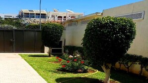 Un jardín bien cuidado con un camino empedrado, setos podados y plantas con flores.