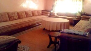 Una sala de estar con un sofá, una mesa de centro redonda y una mesita auxiliar.