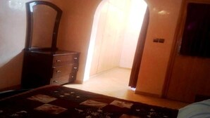 Un dormitorio con cama, cómoda, espejo y un arco que da a otra habitación.