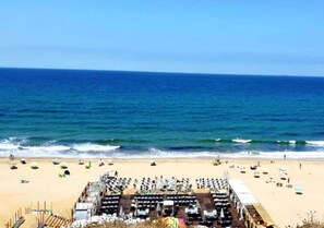 A beach with rows of sun loungers and umbrellas, a clear view of the ocean, and a sandy beach. - Sublime Apartment Beachfront in Tangier 4108 (Tanger)