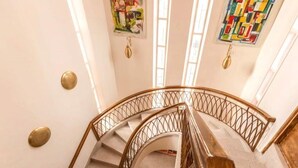 A spiral staircase with a wooden handrail and metal balustrade, leading to an upper floor.