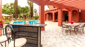 An outdoor patio area with a pool, a bar, and seating arrangements.