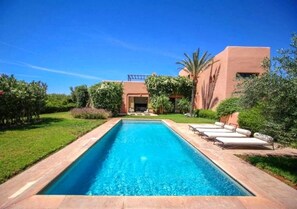 A rectangular swimming pool with a clear blue water surface, surrounded by a well-maintained lawn and a variety of greenery. - Luxurious Villa with pool in Marrakech 4262 (Marrakech)