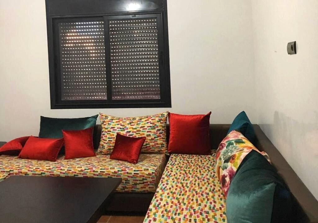 A room with a sofa set, a small table, and a window with a metal grill.