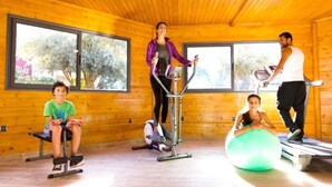 Eine Holzhütte mit einem Fitnessbereich, inklusive Ellipsentrainer, Laufband und Übungsbällen.