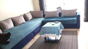 Een woonkamer met een blauwe bank, een gestreept tafeltje en een donkere mat.