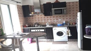 Een keuken met een wasmachine, magnetron en kastjes.