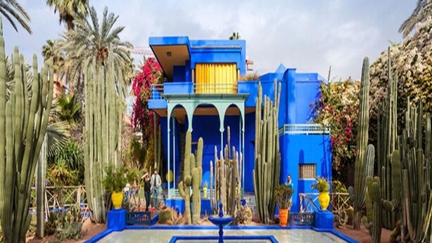 Un edificio blu con archi e una fontana al centro.