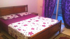 Una camera da letto con un letto, un comodino e una finestra con tende viola.