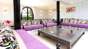 Ein modernes Wohnzimmer mit einem Glastisch, gemusterten Sofas und einem großen Fenster.