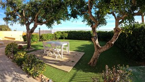 Un espace patio aménagé avec une table et des chaises, entouré d’une pelouse bien entretenue et d’arbres.