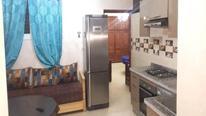 A compact kitchen with a refrigerator, stove, and wooden cabinets. - Apartment 5 minutes from the beach 4253 (Saidia)