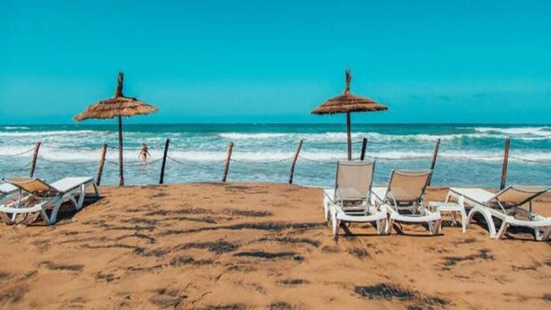 A beach with white lounge chairs and thatched umbrellas. - Apartment 5 minutes from the beach 4253 (Saidia)