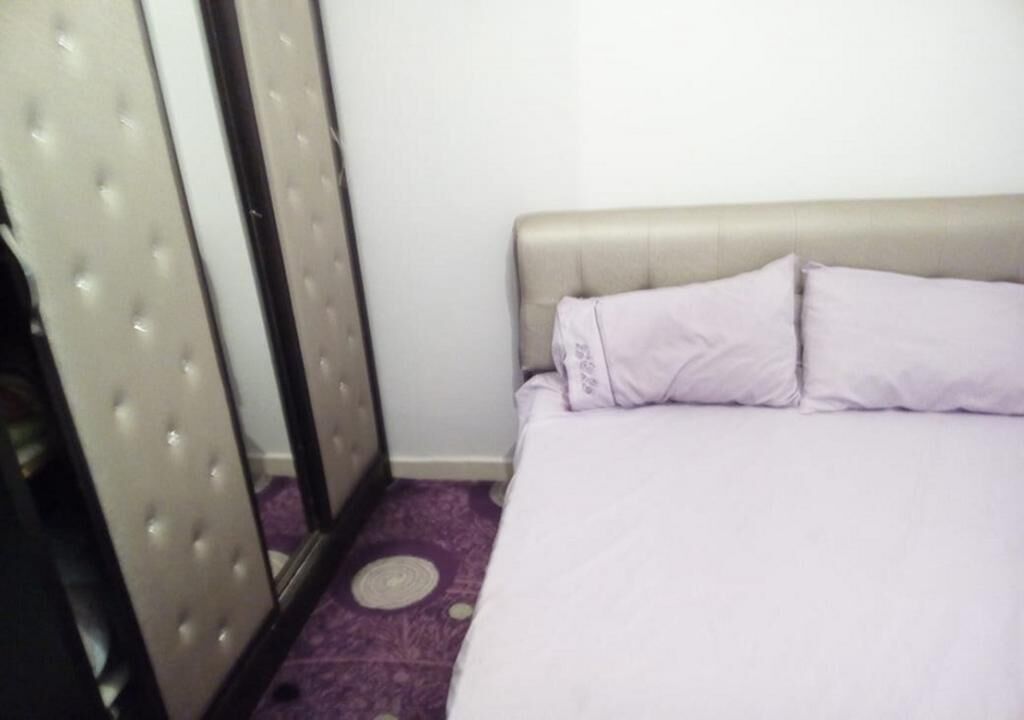 Een slaapkamer met een bed, een spiegel en een paars tapijt.