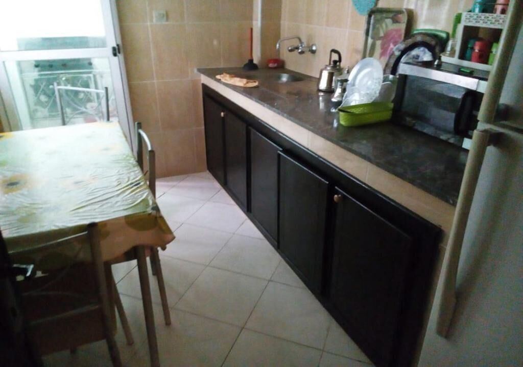A kitchen with a dining table, chairs, a sink, cabinets, and a microwave.